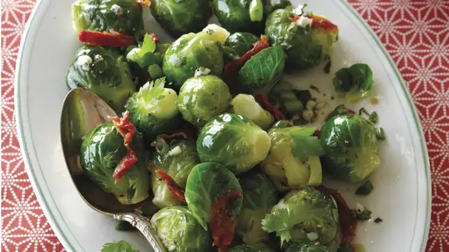 Brussels sprouts with sundried tomatoes on a plate with a spoon