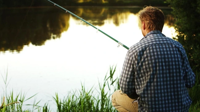 man fishing by the river or lake with his back turned