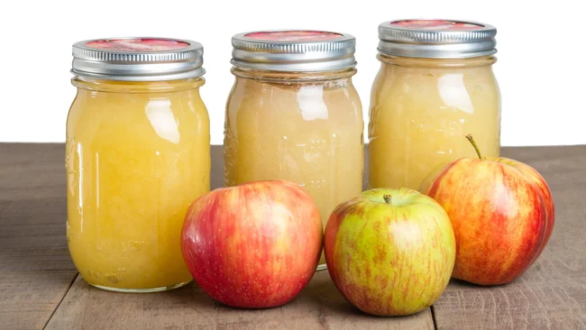 Jars of fresh apple sauce with red apples