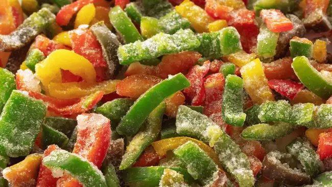 Frozen sliced bell pepper covered with ice. Frozen vegetables background. Selective focus.