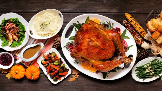 Traditional Thanksgiving turkey dinner. Top view table scene on a dark wood banner background. Turkey, mashed potatoes, dressing, pumpkin pie and sides.